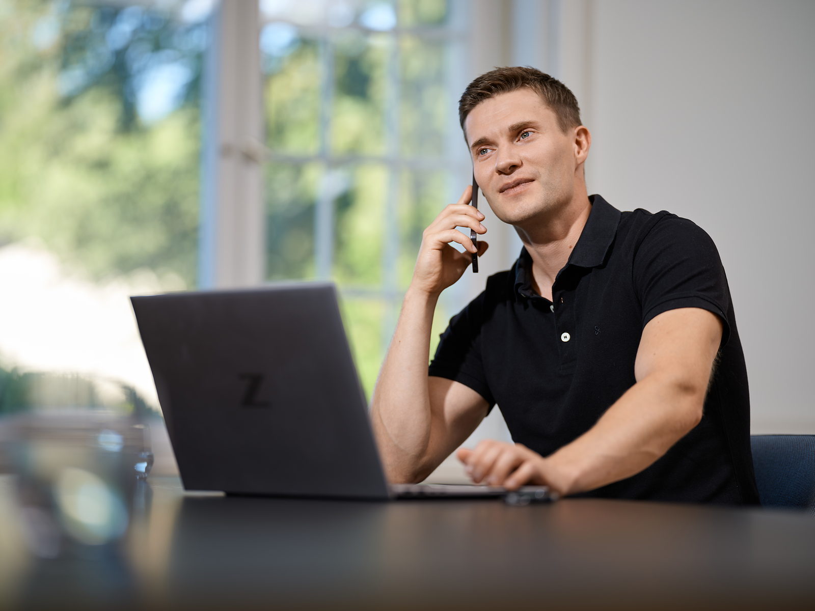 Wolfgang Duttlinger am Schreibtisch im Telefonat vor einem aufgeklappten Laptop